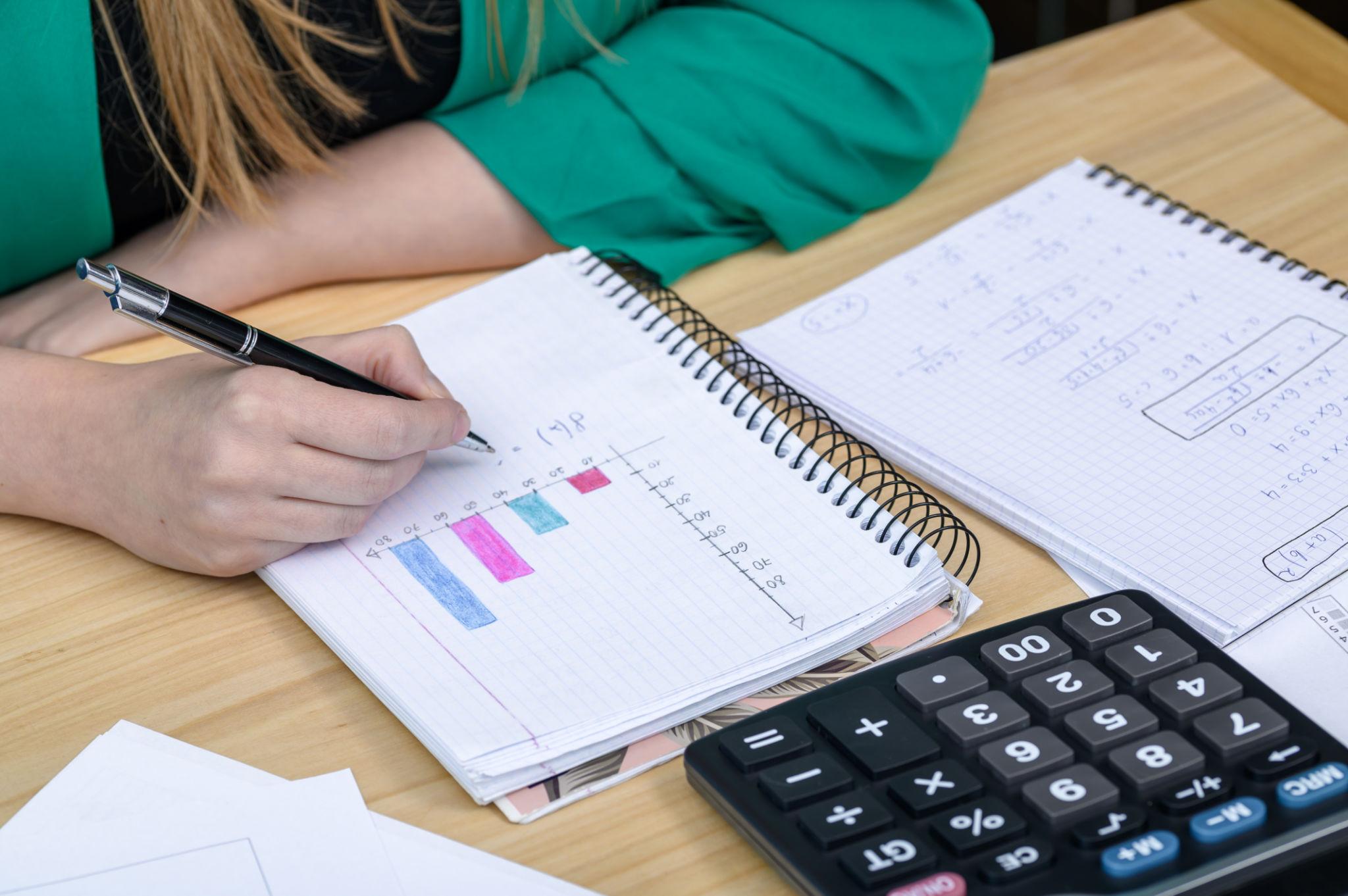 Uczeń zapisujący wykresy i zadania w zeszycie podczas nauki do matury z matematyki